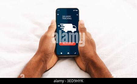Black man using smartphone with delivery tracking app Stock Photo