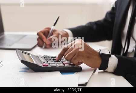 Close up of man checking on incomes, using calculator Stock Photo