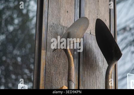 This image features vintage garden tools gracefully hanging on a wooden wall, showcasing their rustic charm and craftsmanship. Perfect for gardening t Stock Photo