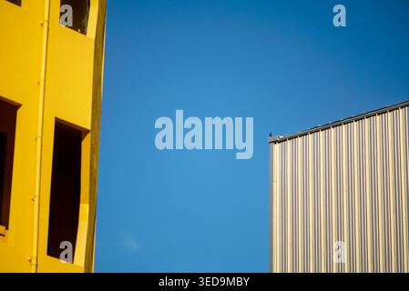 A vibrant architecture photo featuring a yellow building facade contrasting against a blue sky, highlighting modern design, geometric shapes, and urba Stock Photo