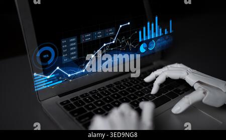 A robotic hand interacts with a laptop displaying dynamic financial data and visualizations, symbolizing the intersection of robotics and modern Stock Photo