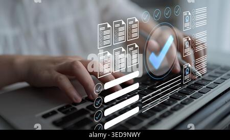 A person engages with a laptop, typing as digital checklists and documents appear on the screen, symbolizing effective project management and task Stock Photo