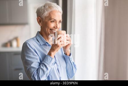 Relaxed smiling mature woman drinking coffee at home Stock Photo