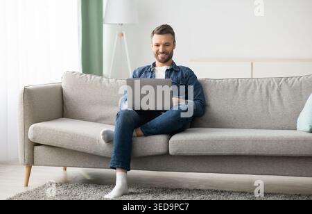 Handsome bearded man using laptop and smiling Stock Photo
