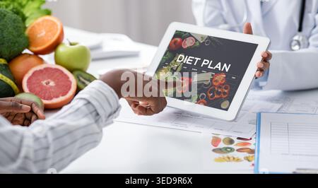 Dietologist Doctor Holding Digital Tablet With Diet Plan App, Patient Choosing Nutrition Stock Photo