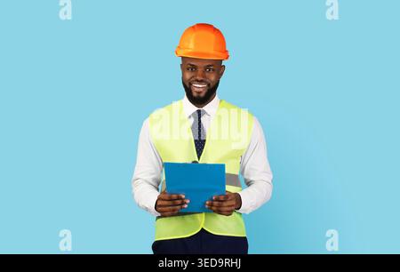 Professions Concept. Handsome Black Engineer In Hard Hat And Vest Holding Clipboard Stock Photo