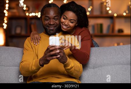 Married black couple using cell phone at cozy winter evening Stock Photo