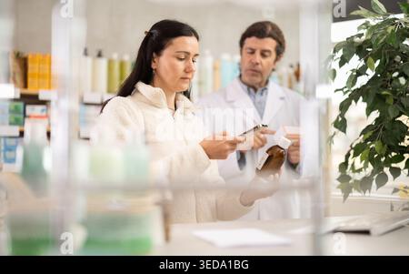 Woman buyer scans syrup qr code with man pharmacist Stock Photo