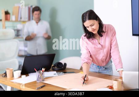 Adult man reviewing document, woman looks construction plan Stock Photo