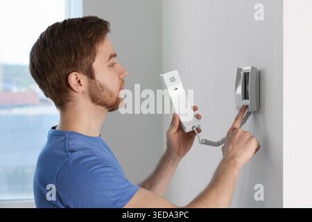 Man pressing button on intercom panel indoors Stock Photo