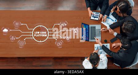 Business professionals collaborating on a low code platform project with charts, laptops, and digital graphics to enhance workflow and efficiency Stock Photo