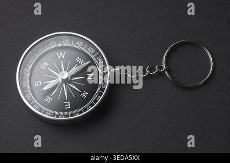 Compass Keychain Isolated on Black Background, Concept of Guidance and Direction Stock Photo