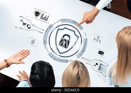 A group of professionals engages in cybersecurity discussions using an interactive table displaying security icons and data, emphasizing collaboration Stock Photo