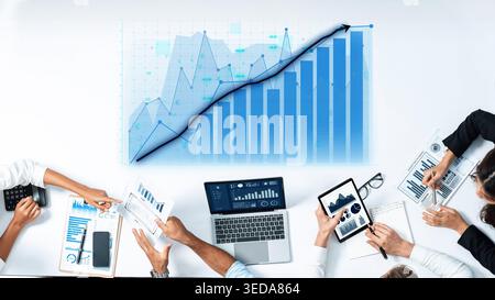 A diverse business team collaboratively engages in analyzing financial data, using technology and visual graphs within a modern office environment Stock Photo