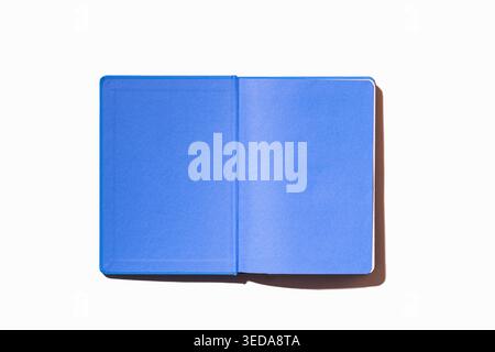 Open blue ultramarine hardcover notebook with blank white pages on white background, overhead flat lay with copy space for writing or design ideas Stock Photo