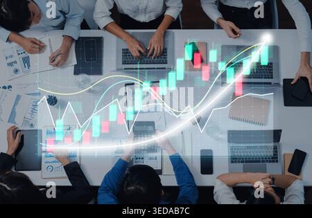 A high-angle view of professionals collaborating on financial analysis, featuring laptops, notebooks, and vibrant charts, symbolizing teamwork and Stock Photo