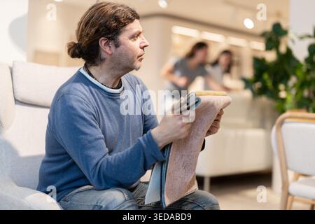Man sitting in an armchair choosing fabric for sofa Stock Photo