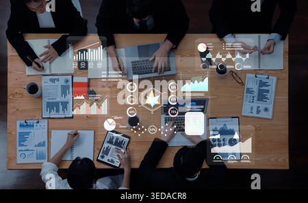 Diverse professionals collaborate in a modern office, analyzing data trends and financial reports. The meeting highlights teamwork and technology Stock Photo