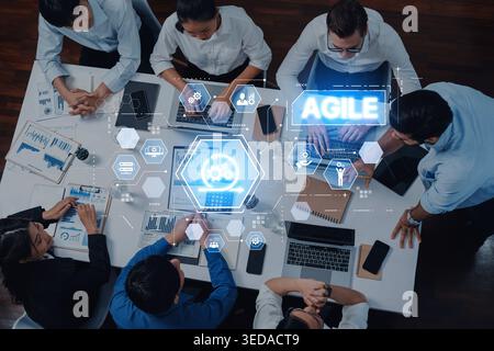 A diverse group of professionals engages in collaborative work using digital tools in an agile workspace, promoting effective communication and Stock Photo