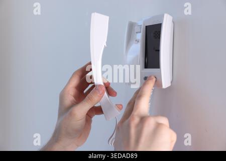 Man with handset pressing button on intercom panel indoors, closeup Stock Photo