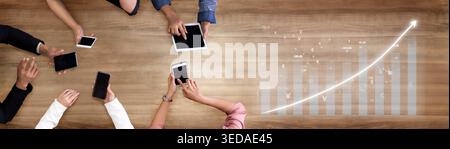 A collaborative workspace showcasing hands interacting with digital devices on a wooden table, representing growth and analysis through data Stock Photo
