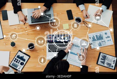 A dynamic business meeting scene featuring professionals engaged in discussions with laptops and data analysis tools, highlighting teamwork and Stock Photo