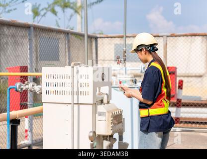 Industrial technician or inspector conducting a safety audit and equipment check at an outdoor factory utility station. Stock Photo