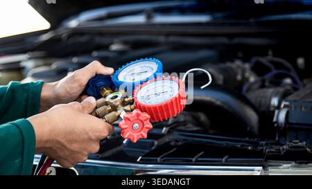 Mechanic checking car air conditioning system with manifold gauges Stock Photo