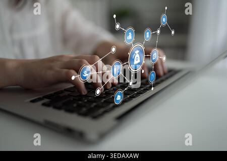 Close-up of hands typing on a laptop keyboard with floating virtual financial icons. This image represents the intersection of technology and finance Stock Photo