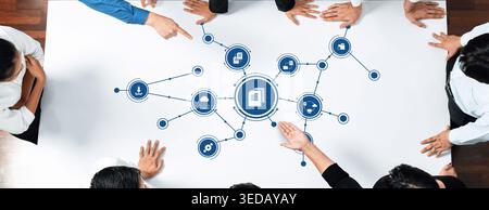 A diverse team engages in a collaborative management strategy session, analyzing data connections on a white table, showcasing teamwork and innovative Stock Photo