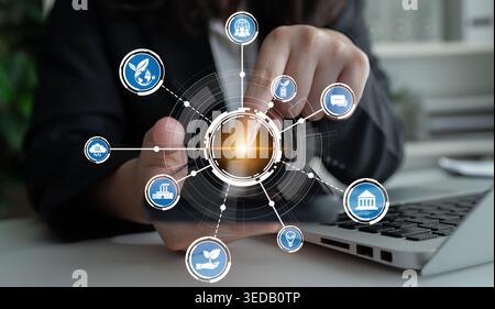 A businesswoman interacts with modern technology in an office, showcasing digital connectivity through graphical icons that represent various sectors Stock Photo