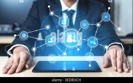 A business professional interacts with a tablet displaying a digital network, symbolizing technological advancement and data connectivity in an office Stock Photo