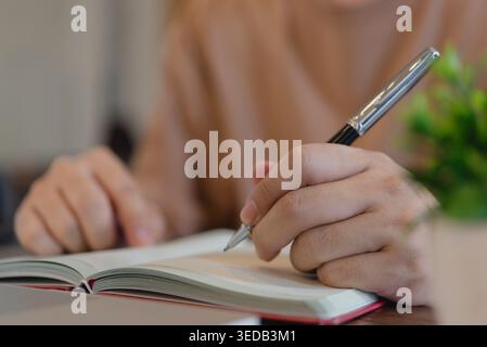 man hand writing in notebook with pen. Student studying or business person taking notes on paper at desk. Planning daily agenda, checklist and diary j Stock Photo