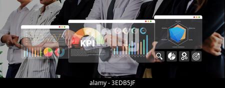 A business team examines key performance indicators displayed on digital screens, highlighting collaboration, strategic planning, and data-driven Stock Photo