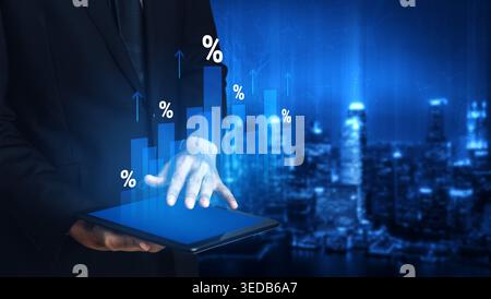 A businessman interacts with a tablet displaying dynamic financial growth graphics, set against an illuminated city skyline, symbolizing technology Stock Photo