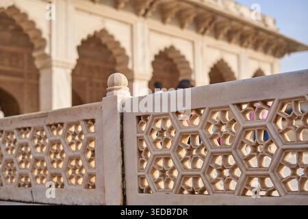 Close-up view of intricate white marble lattice work (jali) featuring hexagonal geometric patterns, with a traditional Indian Mughal architectural Stock Photo