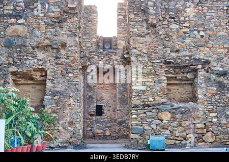 Weathered stone wall of an ancient ruin or historic building facade constructed from irregularly shaped stones in various earth tones including Stock Photo
