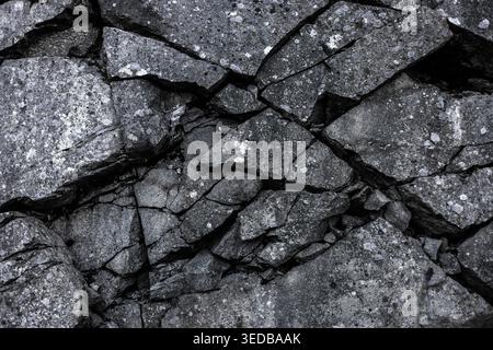 Extreme Close-Up of Cracked and Weathered Dark Granite Rock Face with Natural Fissures Stock Photo