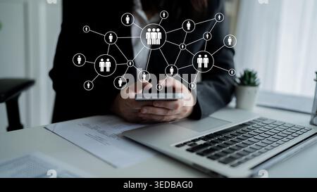 A professional individual engages with a smartphone while surrounded by digital network symbols, emphasizing connectivity and collaboration in a Stock Photo
