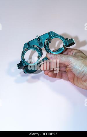 Man Hand Holding A Pair of Test Glasses on a Pink Table Stock Photo
