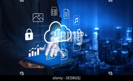 A businessman interacts with a tablet displaying cloud technology symbols, showcasing digital data management and security within a modern cityscape Stock Photo