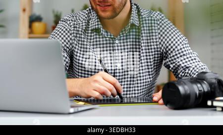 Person works on graphic design using tablet and laptop at home office in daytime Stock Photo