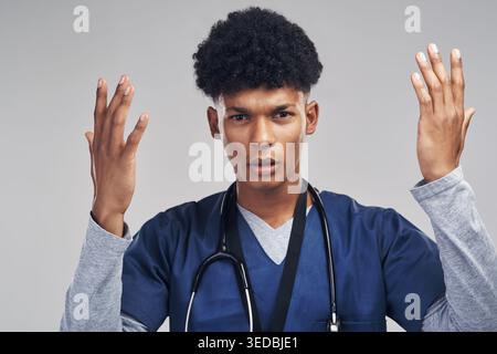 Nurse, confused and portrait of man in studio for healthcare, medical question or serious choice. Male person, gesture or frustrated surgeon on grey Stock Photo