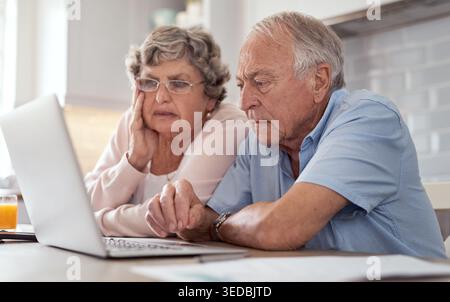 Confused, internet and old couple in kitchen, laptop for financial planning or frustrated. Online bills, elderly man or woman in home, email or pc for Stock Photo