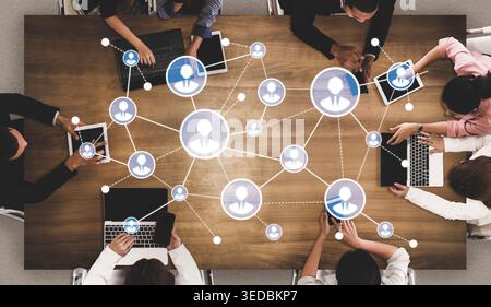 A modern office scene showcasing diverse individuals networking and collaborating with various digital devices, symbolizing communication and teamwork Stock Photo