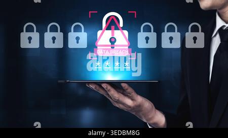 A businessman holds a tablet displaying a cybersecurity warning about data breaches, highlighted by padlocks, symbolizing the importance of data Stock Photo