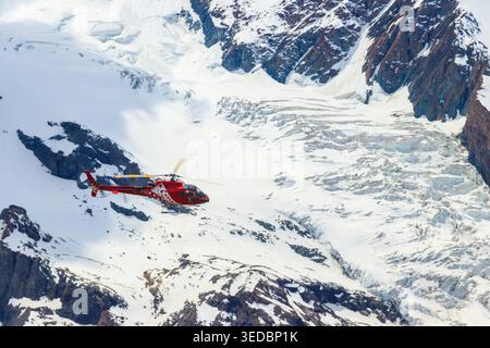 Helicopter flying over the snowy Swiss Alps in Switzerland Stock Photo