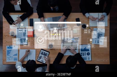 A high-angle view of a business meeting with diverse professionals engaging in data discussion and project planning using modern digital tools and Stock Photo