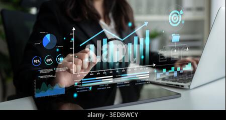 Business professional analyzing data with digital charts and graphs in an office setting showcasing modern analytics and technology tools for decision Stock Photo