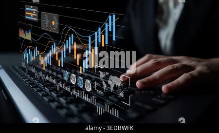 A business professional examines complex financial charts on a laptop, demonstrating digital data visualization in a modern office environment. Gantry Stock Photo